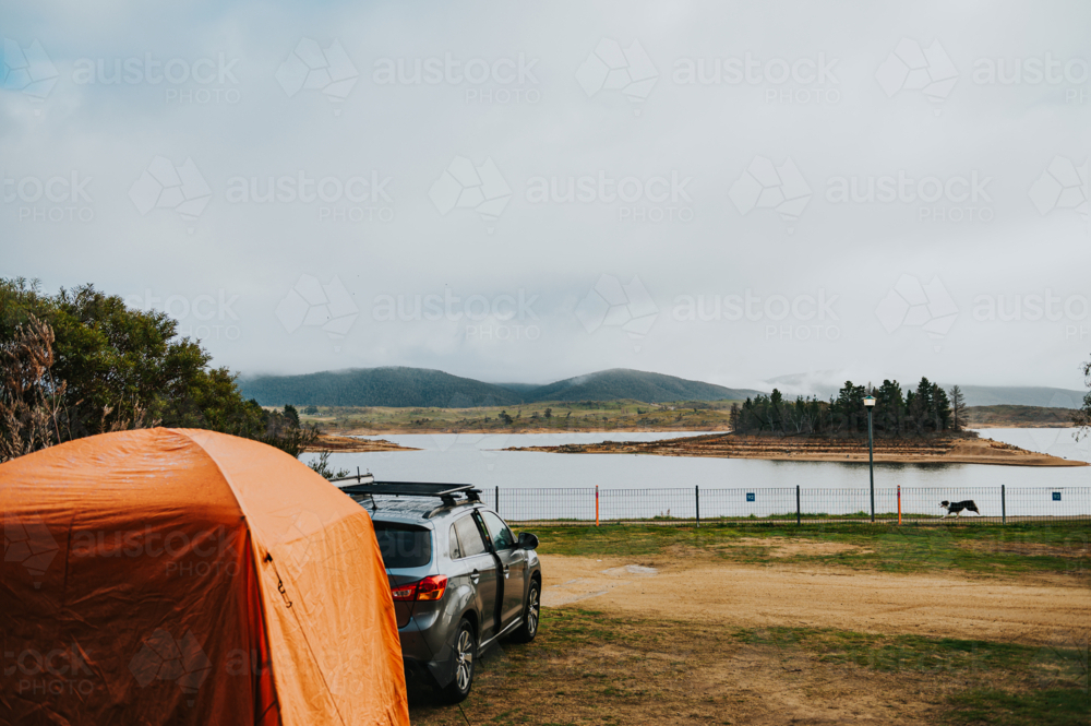 a car and a tent on a camping site in front of a lake on a winter day - Australian Stock Image