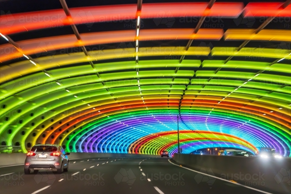 A car driving through a tunnel lit with rainbow coloured lights - Australian Stock Image