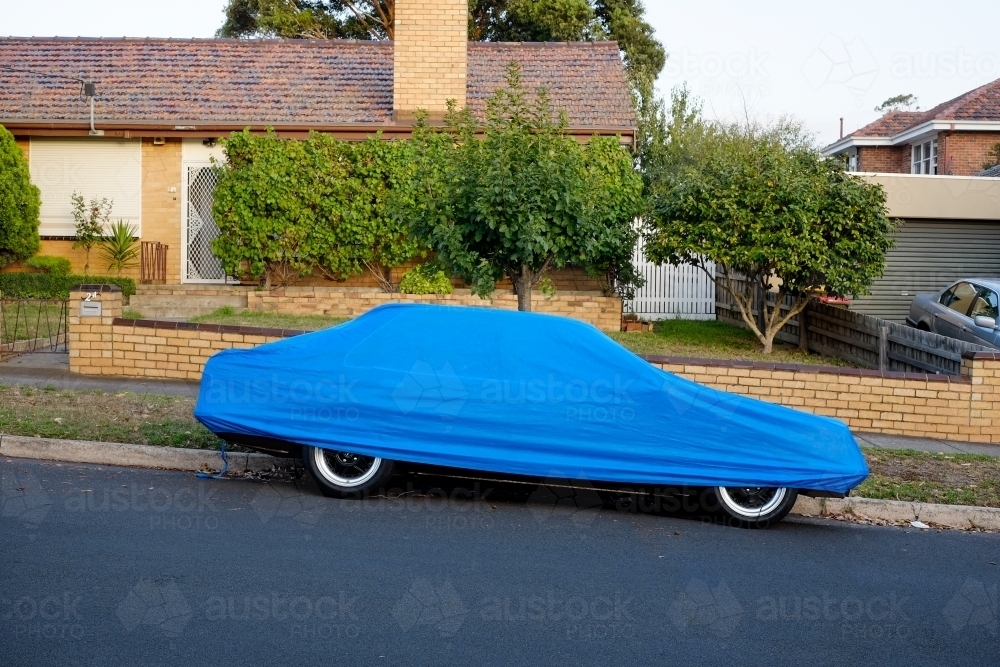 A car parked on the street under a blue cover - Australian Stock Image