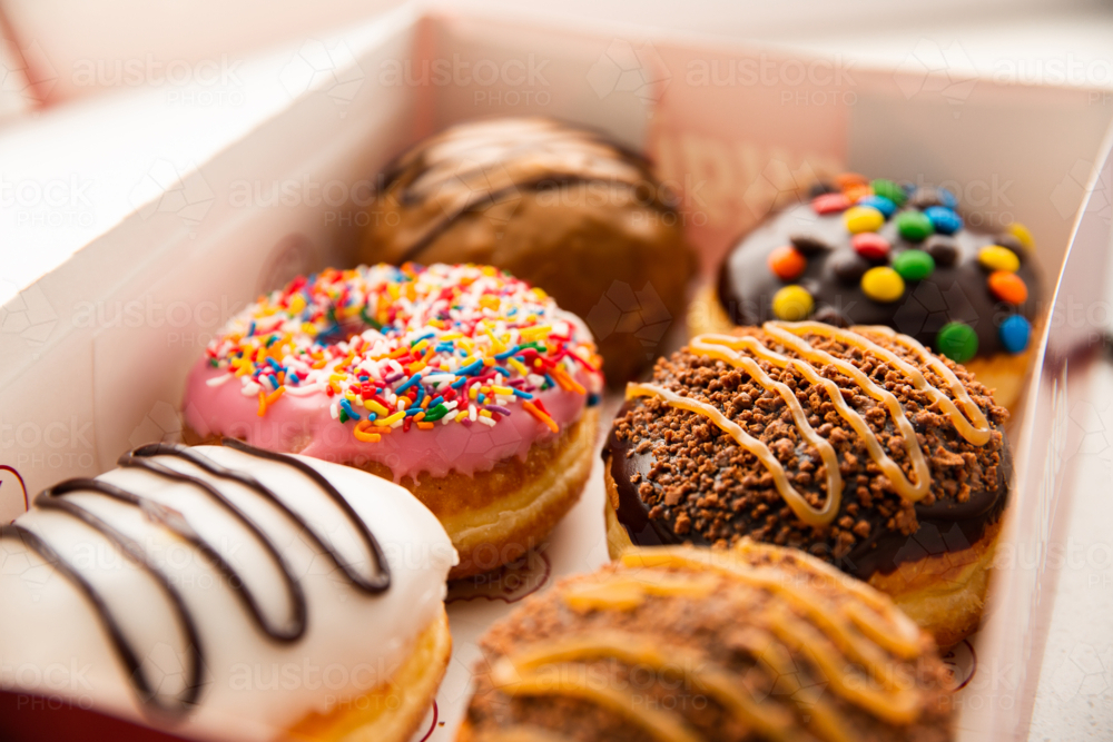 a cardboard box with 6 assorted doughnuts inside - Australian Stock Image