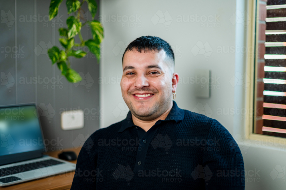 A cheerful man seated at his desk in a comfortable home office - Australian Stock Image