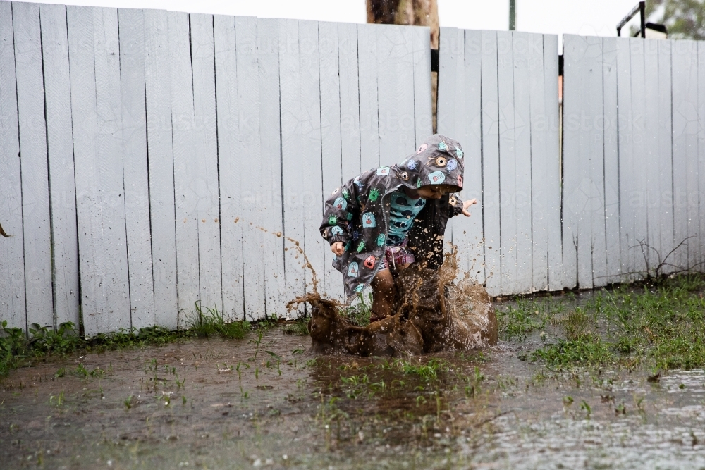 a child making a huge splash in a muddy puddle - Australian Stock Image