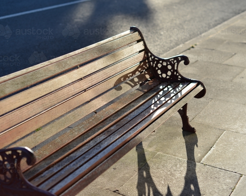 A classic wooden public bench in the afternoon sun - Australian Stock Image