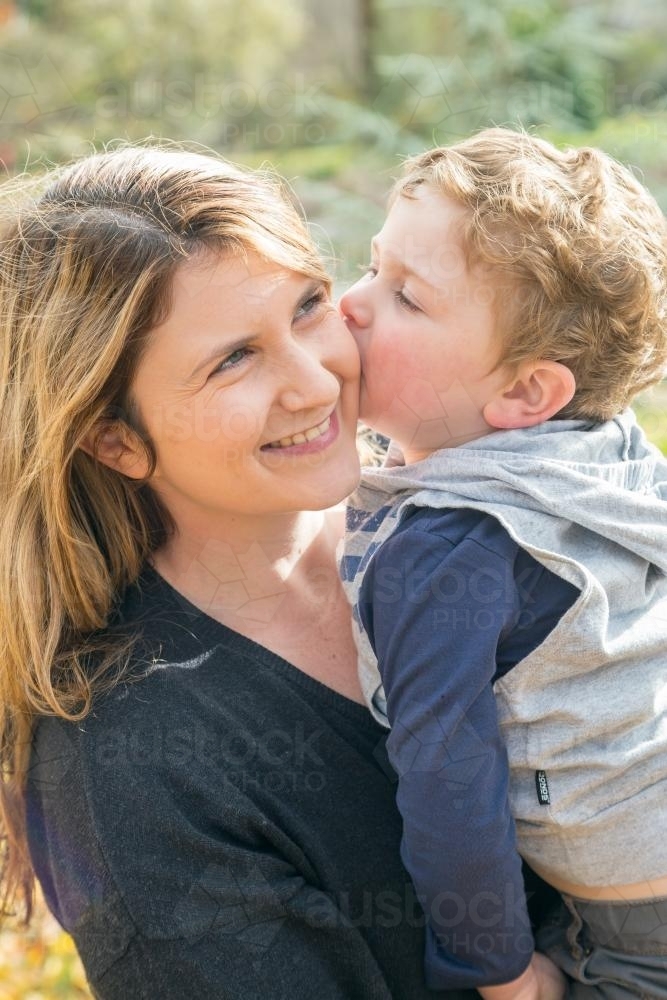 A close up of a boy kissing his mother - Australian Stock Image