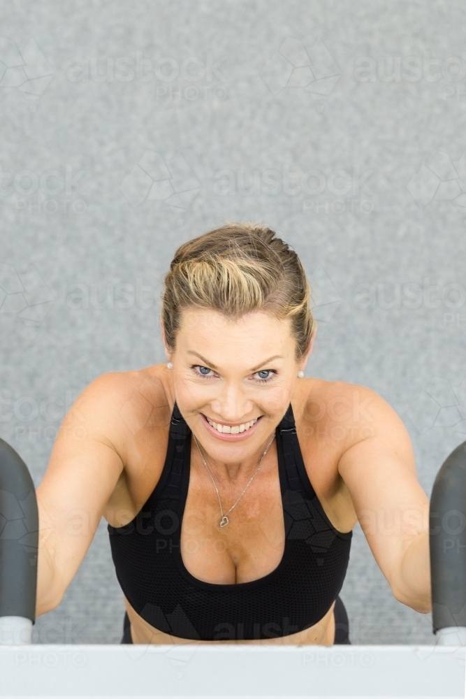 A close up of a fit woman's face doing chin ups in a gym - Australian Stock Image