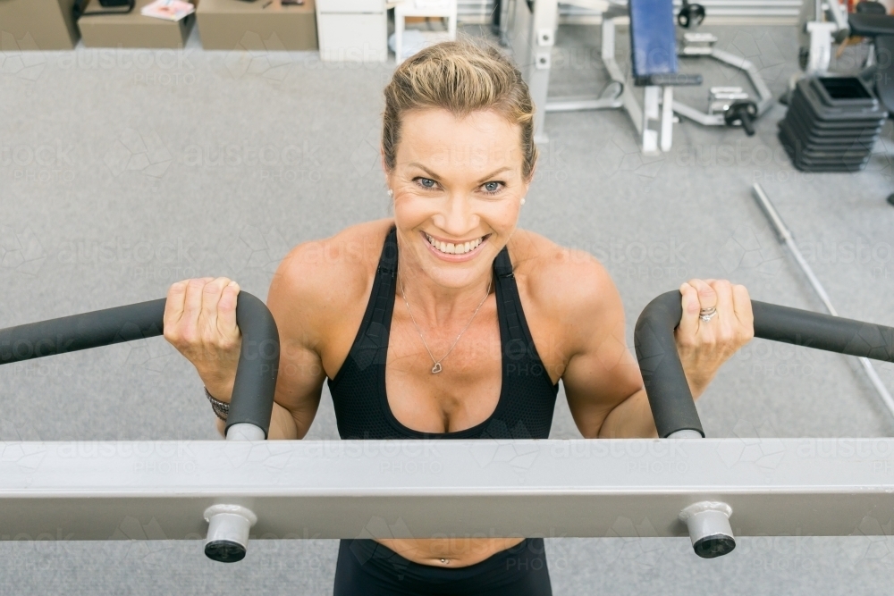 A close up of a fit womans face doing chin ups in a gym - Australian Stock Image
