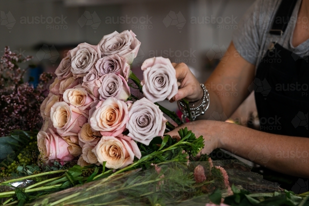 A close up of a person arranging a beautiful bunch of roses - Australian Stock Image