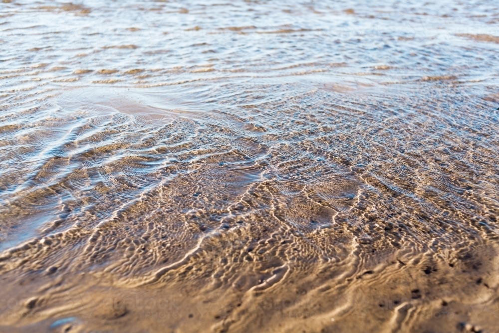 A close up of water ripples of a river at low tide. - Australian Stock Image