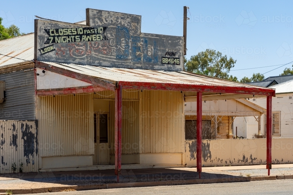 A closed mixed business with wide veranda, tin over its windows and paint peeling off - Australian Stock Image