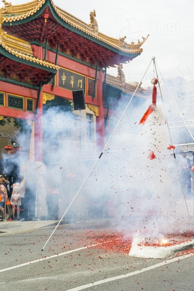 A cloud of smoke rising from a string of firecrackers going off in front of a Chinese building - Australian Stock Image