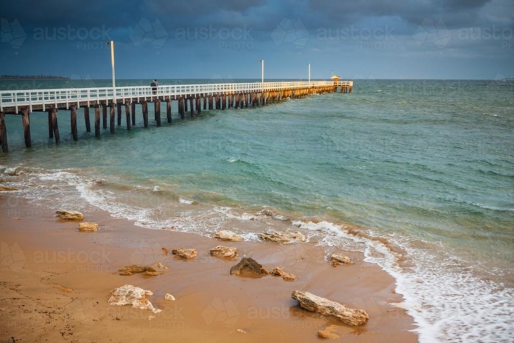 A coastal jetty under dark clouds - Australian Stock Image
