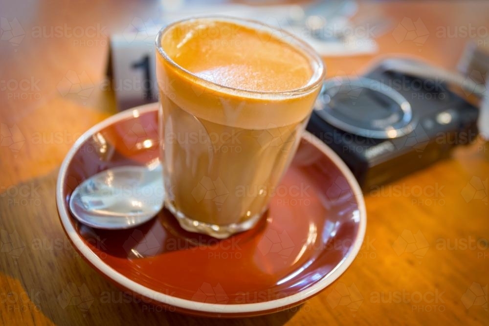A coffee and camera lying on a table in a cafe - Australian Stock Image