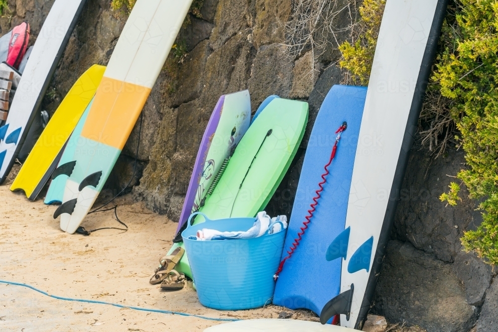 Image of a collection of surfboards and boogie boards leaning against a