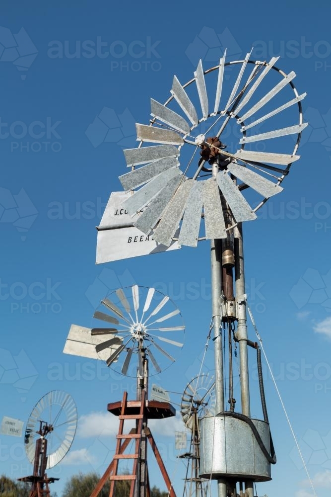 A collection of tin windmills with blue sky behind - Australian Stock Image