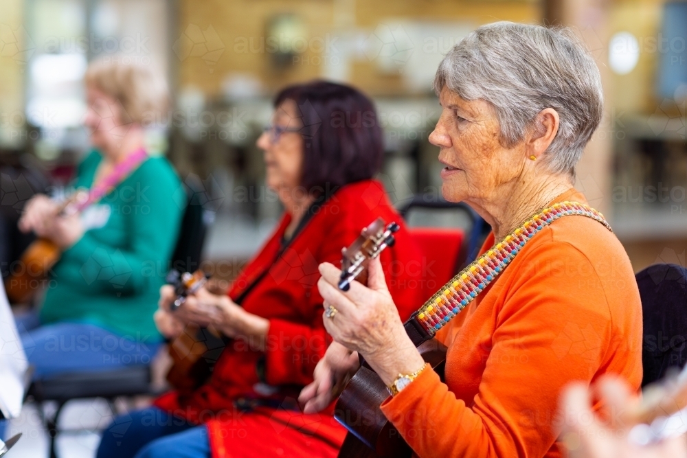 a colourful group of senior women playing ukulele - Australian Stock Image