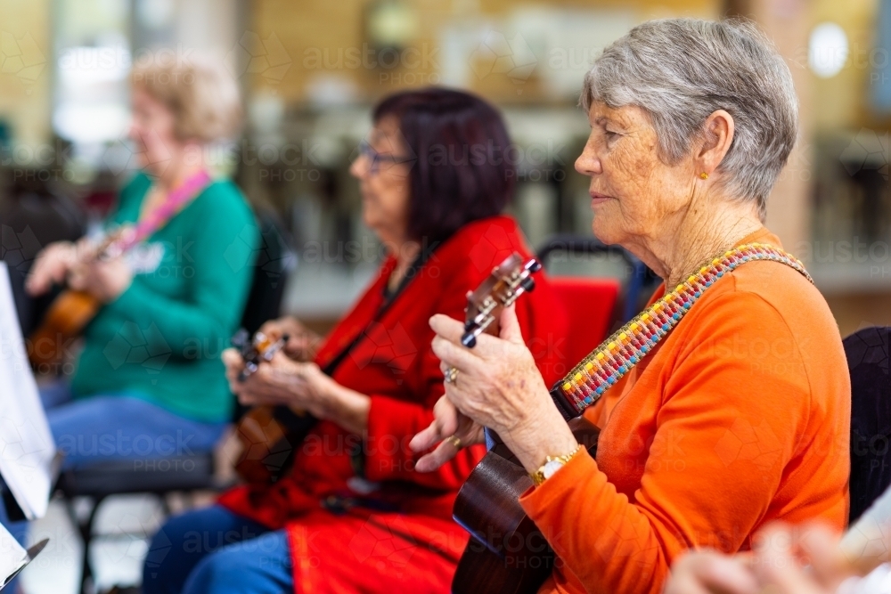 a colourful group of senior women playing ukulele - Australian Stock Image