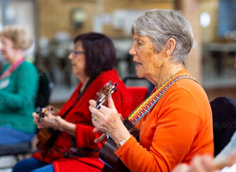 Image of a colourful group of senior women playing ukulele Austockphoto