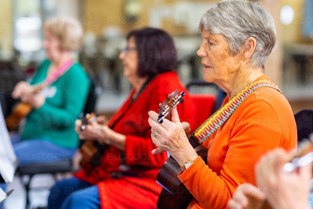 a colourful group of senior women playing ukulele - Australian Stock Image