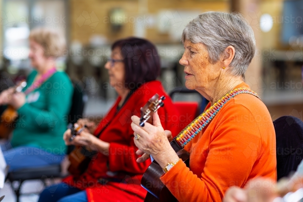 a colourful group of senior women playing ukulele - Australian Stock Image