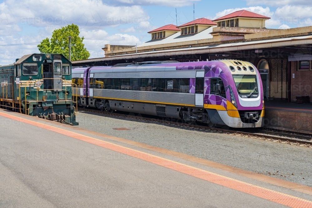 A commuter train and a diesel locomotive waiting at a railway platform - Australian Stock Image