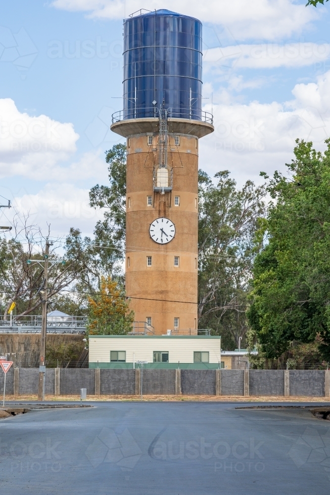 A concrete water tower with a tank on top and a clock on the side - Australian Stock Image