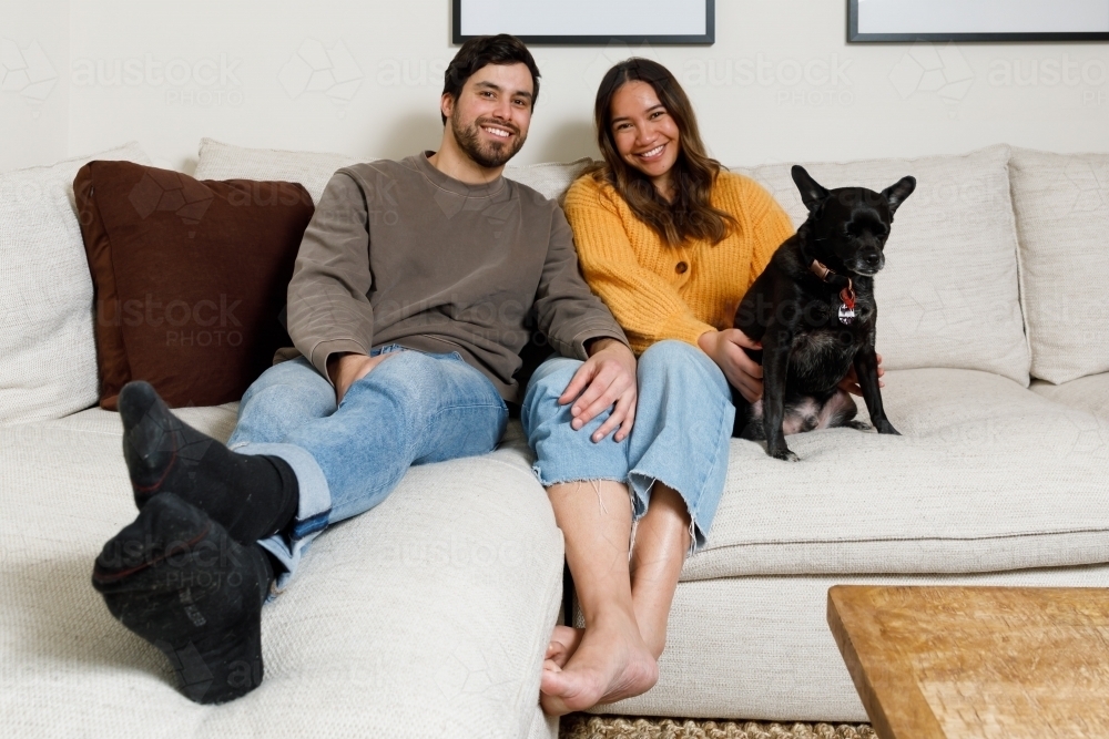 A couple at home on a couch with their dog - Australian Stock Image