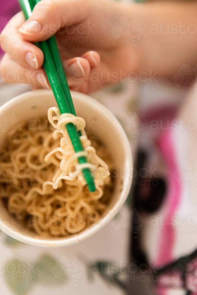 a cup of instant ramen noodles and chopsticks - Australian Stock Image