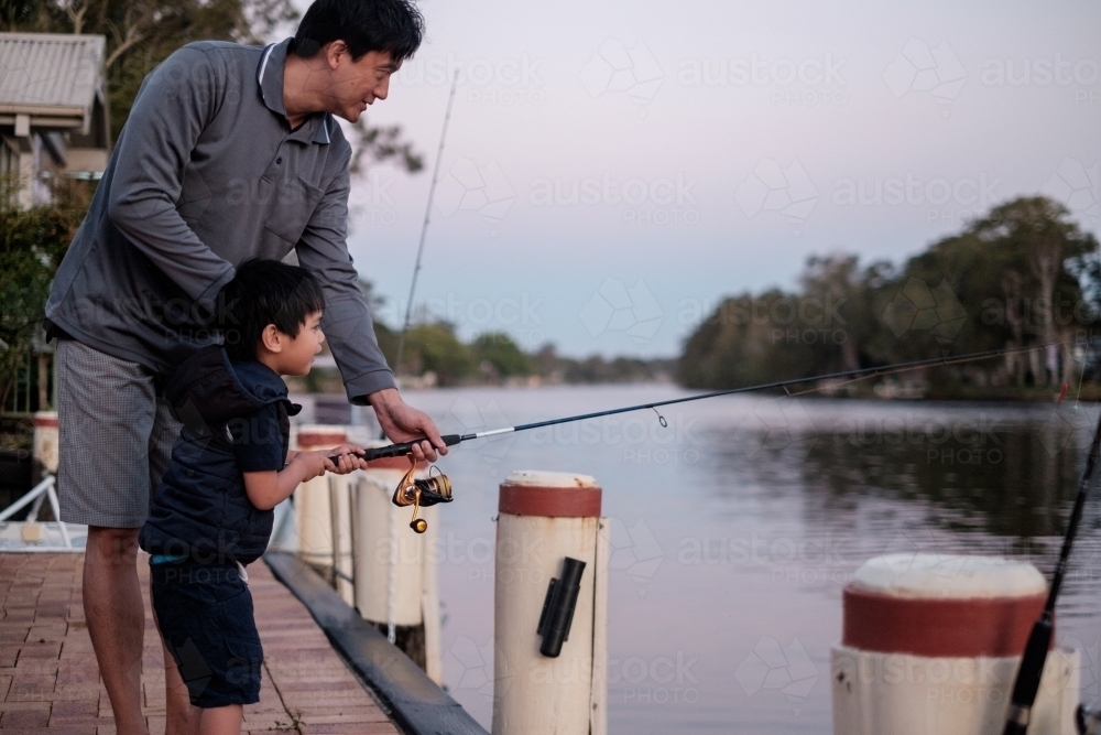 a curious kid being taught how to fish - Australian Stock Image