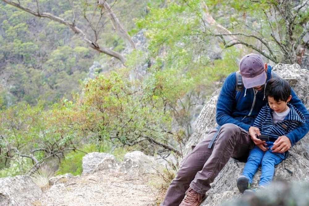 A dad, teaching his son how to use a device on a hiking trail - Australian Stock Image