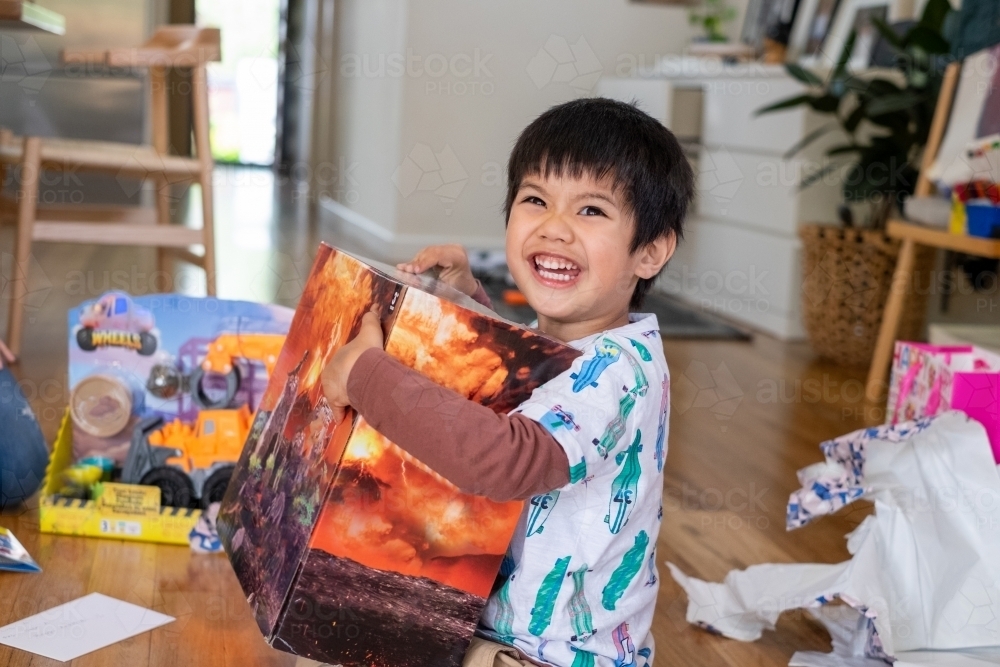 a delighted kid opening presents on his birthday - Australian Stock Image