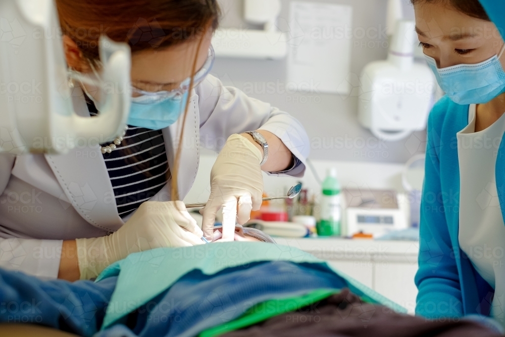 A dentist and her assistant attending to a patient - Australian Stock Image