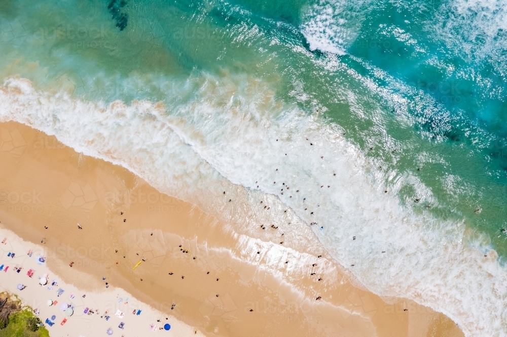 A diagonal look down on a busy beach day as the surf comes in. - Australian Stock Image