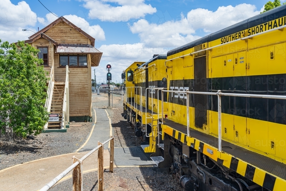 A diesel locomotive sitting next to an old fashion signal box at a regional railway station. - Australian Stock Image