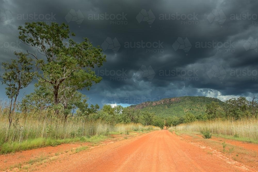 A dirt road through Southern Kakadu with storm clouds - Australian Stock Image