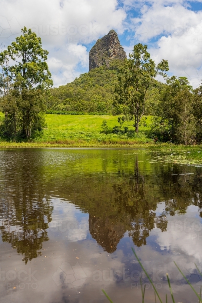 A distant pointed mountain reflected in a still waterhole - Australian Stock Image