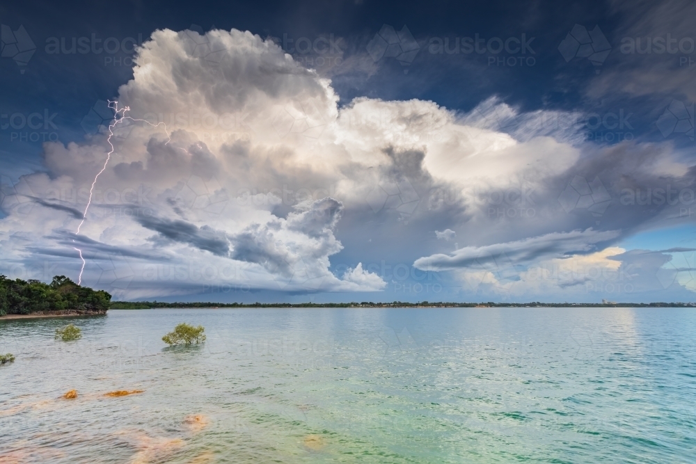 A distant thunderstorm over the ocean with lightning strike - Australian Stock Image