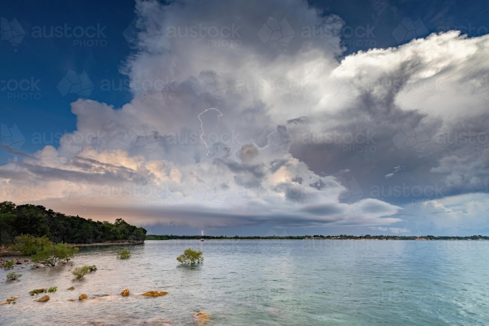 A distant thunderstorm over the ocean with lightning strike - Australian Stock Image