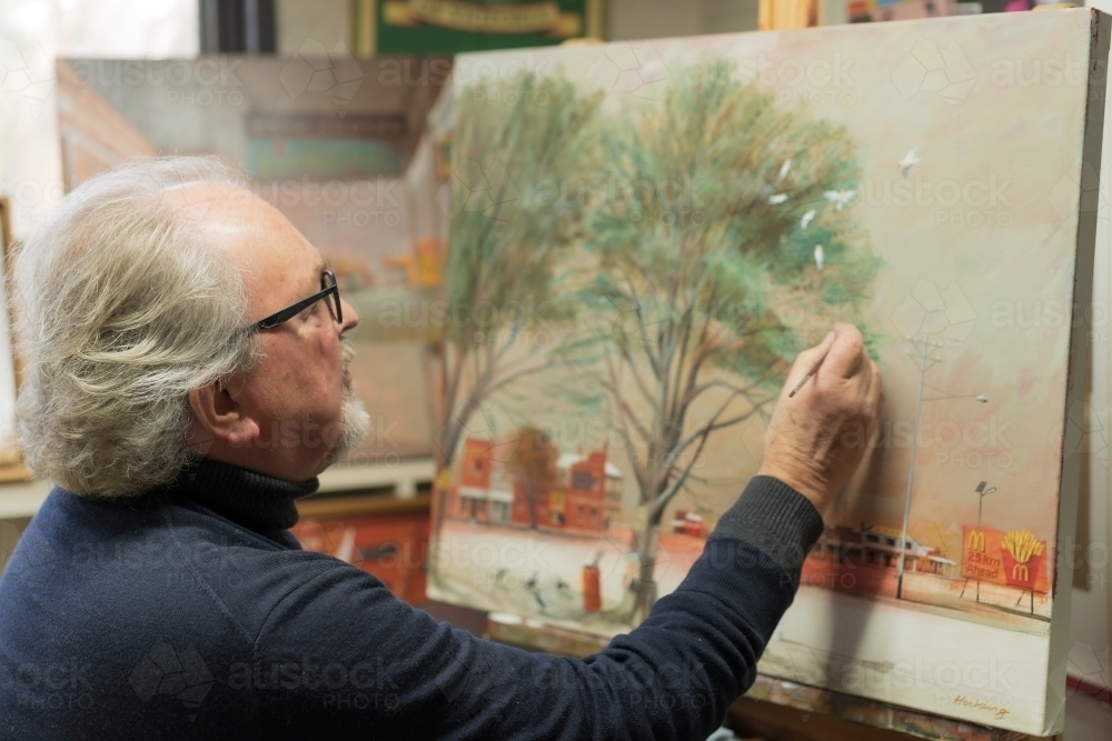 A distinguished male artist painting a canvas in an art studio - Australian Stock Image