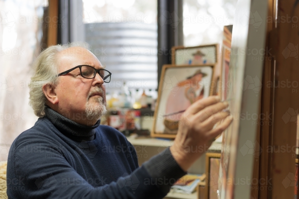 A distinguished male artist painting a canvas in an art studio - Australian Stock Image