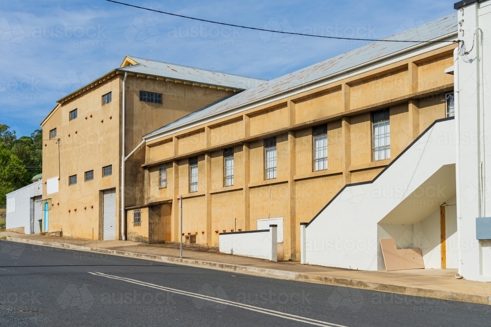 A dominant factory facade in a side street with concrete walls and outdoor staircase - Australian Stock Image