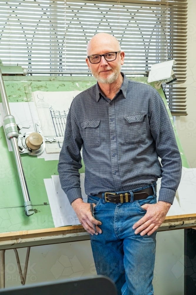 A draftsman standing proudly in front of his drawing board - Australian Stock Image