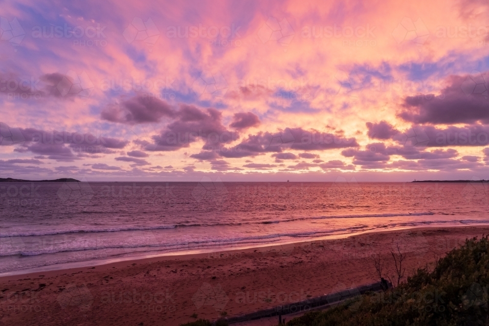 A dramatic colourful sunset over the ocean between two distant land points - Australian Stock Image