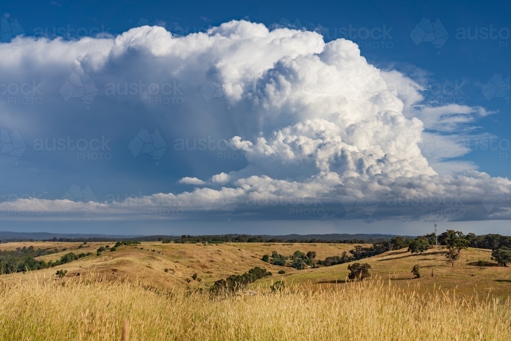 A dramatic storm cloud building over a dry rural hillside - Australian Stock Image