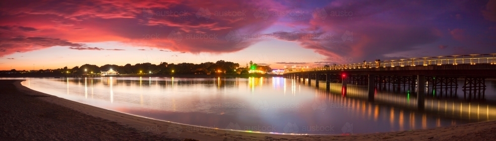 Image of A dramatic sunset sky and bridges reflected in the still ...