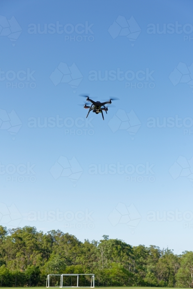 A drone, or UAV, or RPAS hovering over a football field - viewed close up unmanned aerial vehicle - Australian Stock Image