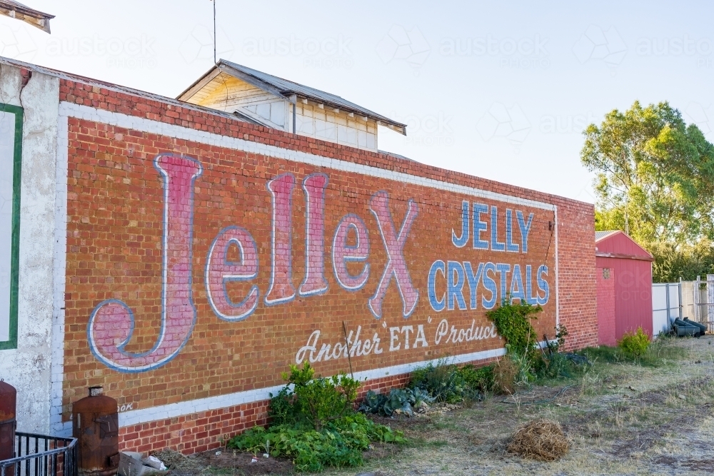 A faded hand painted sign covering a long brick wall - Australian Stock Image