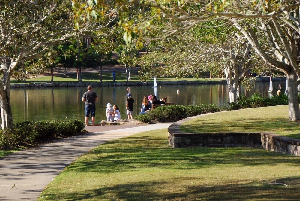 A Family down by the lake feeding ducks - Australian Stock Image