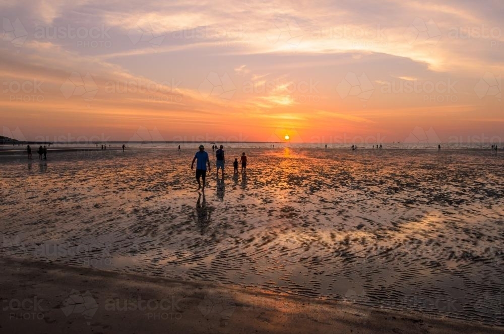 A family silhouetted in the sunset at a beach - Australian Stock Image