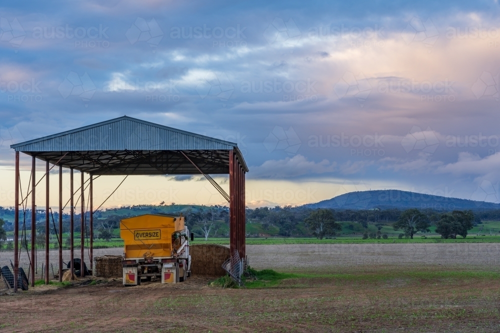 A farm truck under a hay shed on rural farmland at twilight - Australian Stock Image