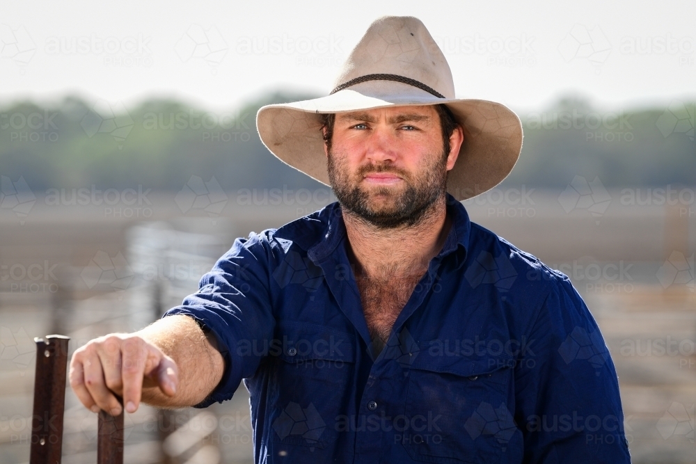 A farmer leans on an iron post during the drought - Australian Stock Image